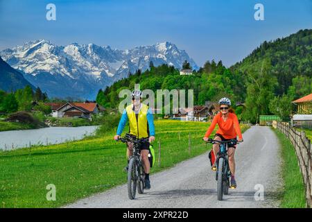 Mann und Frau Radfahren auf dem Bodensee-Königssee-Radweg entlang der Loisach, Zugspitze im Hintergrund, Eschenlohe, Oberbayern, Bava Stockfoto