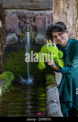 Frau im Kostüm der Figur „Prinzessin“ aus dem Märchen „der Froschprinz“ der Brüder Grimm posiert am Brunnen Steinau an der Straße Stockfoto