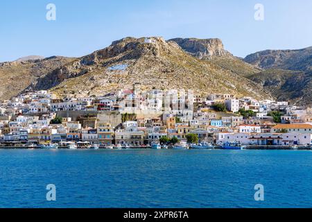 Inselhauptstadt Póthia, weiße Kapelle und gemalte griechische Flagge auf dem Hügel über Pothia mit Yachthafen auf der Insel Kalymnos (Kalimnos) in Griechenland Stockfoto