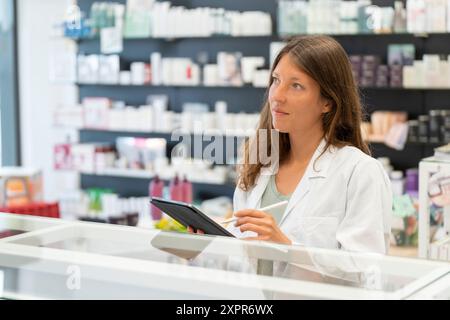 Apothekerin mit Tablette zur Beratung in einer gut sortierten Apotheke Stockfoto
