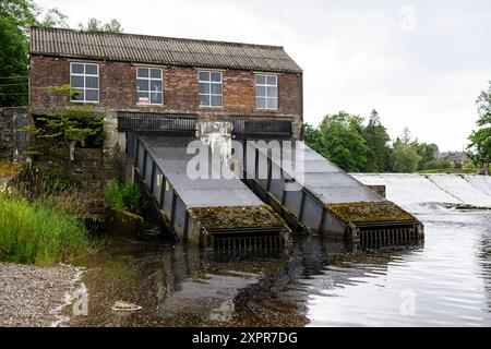 Grassington Yorkshire UK-27. Juli 2024. Altes Industriebau, Wasserkraft am Fluss, umgeben von üppigem Grün unter einem bewölkten Himmel. Stockfoto