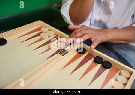 Detaillierte Aufnahme einer Frau, die in einem Backgammon-Spiel teilnimmt, wobei ihre Hand und die Spieleinstellungen hervorgehoben werden. Ideal für Freizeitkonzepte, Strategien und Wettkämpfe Stockfoto