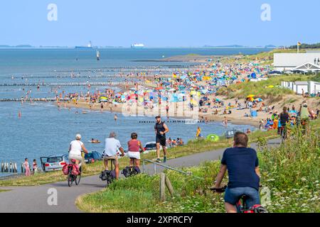 Radfahrer und Touristen schwimmen und sonnen am Strand entlang der Westerschelde bei Breskens an einem heißen Tag in den Sommerferien, Zeeland, Niederlande Stockfoto