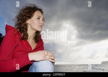 Absorbiert, Erwachsene, Brünette, Brünette, Kaukasier, Kaukasier, Wolken, Farbe, Farbe, zeitgenössisch, lockiges Haar, dunkelhaarig, tagsüber, Erw Stockfoto