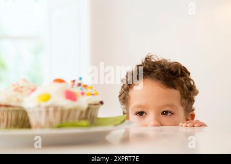 Vier Jahre alter Junge wartet auf einen cupcake Stockfoto