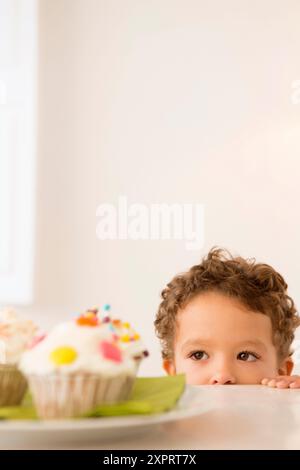 Vier Jahre alter Junge wartet auf einen cupcake Stockfoto