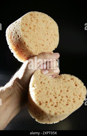 Man drückt einen trockenen Schwamm zusammen Stockfoto
