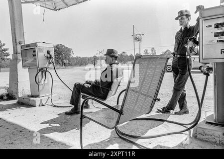 Mazedonien, Arkansas, USA – 23. Juni 2024: Horizontaler Schuss von zwei Männern, die 1975 auf den nächsten Kunden warten, der Gas benötigt. Einer sitzt da Stockfoto