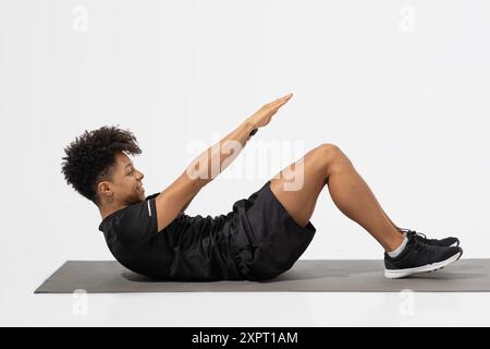Junger Mann, der Kernübungen auf Matte im Bright Studio durchführt Stockfoto