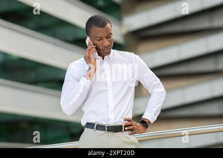 Junger Mann mit weißem Hemd, der in einem ernsthaften Telefonanruf verwickelt ist Stockfoto