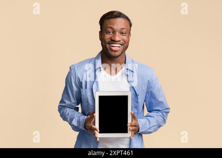 African American Guy zeigen Tablet Bildschirm leer stehend, Studio, Mockup Stockfoto