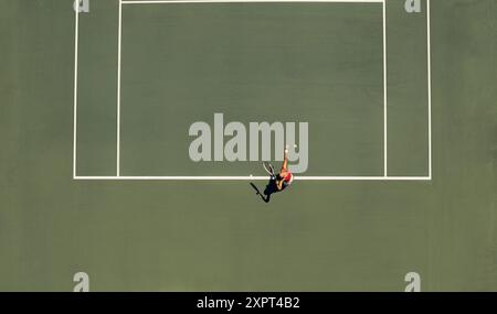 Aus der Vogelperspektive eines Tennisspielers, der während eines Spiels an einem sonnigen Tag auf einem Platz dient, zeigt Konzentration und Leichtathletik. Stockfoto