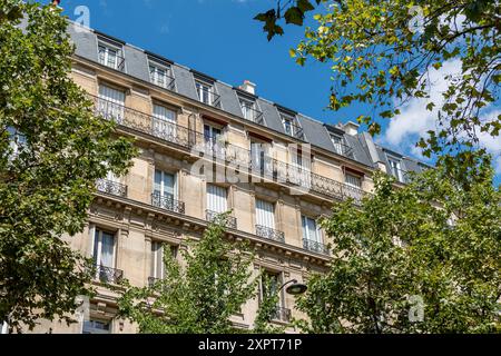 Fassaden von Apartmentgebäuden im klassischen Pariser Stil entlang einer von Bäumen gesäumten Allee. Das Konzept des Wohnimmobilienmarktes für Altwohnungen in Frankreich Stockfoto