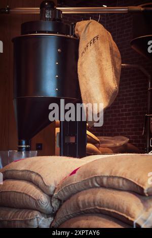 Kaffeerösterei und Sackbeutel mit Kaffeebohnen im Coffee Shop-Lager Stockfoto