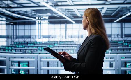 Computerwissenschaftler, der die Überprüfung durchführt und Daten auf Tablets mit den erforderlichen Fehlerbehebungen im Server-Hub eingibt. Frau, die im Rechenzentrum arbeitet und eine fortschrittliche Datenspeicherinfrastruktur zur Unterstützung von IT-Workloads bietet, Kamera B Stockfoto