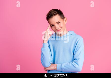 Foto-Porträt des charmanten Teenager-Jungen-gesinnten Touch-Tempelgeste gekleidet stilvolles blaues Kleid isoliert auf rosa Farbhintergrund Stockfoto