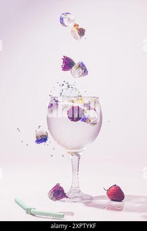 Eiswürfel fallen und spritzen in ein klares Cocktail-/Weinglas. Dieses Bild hat einen weißen Hintergrund und ist ideal zum Kopieren. Stockfoto