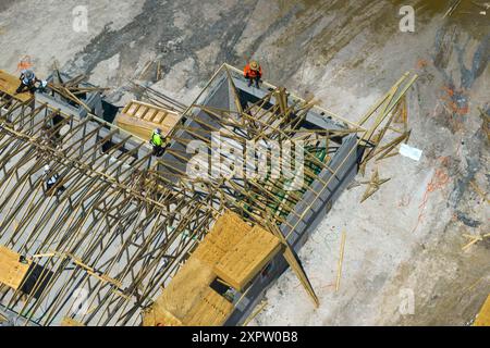 Bauarbeiter, die an der Dachkonstruktion eines unfertigen Wohnhauses mit Holzrahmenstruktur im Vorstadtgebiet von Florida arbeiten. Wohnungsbau Stockfoto