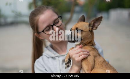 Junge kaukasische Frau, die einen kleinen Hund in der Hand hält. Stockfoto