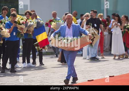 Otopeni, Rumänien. 7. August 2024: Ein Mann mit einer Blumenkasten bei der Ankunft der rumänischen Ruder-, Gymnastik- und Tischtennismannschaften der Olympischen Spiele Paris 2024 am Flughafen Bukarest Henri Coanda in Otopeni, Rumänien. Quelle: lcv/Alamy Live News Stockfoto