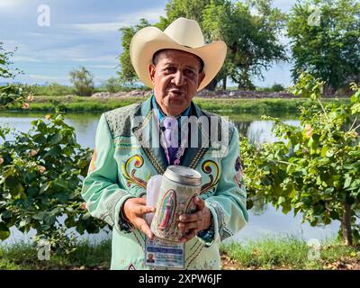 Jhon Smith Noriega posiert am 14. Juli 2024 für ein Porträt neben dem oberen Kanal in der Laguna del Nainari in der Stadt Obregón, Sonora, Mexiko. Jhon trägt ein Kostüm der beliebten oder regionalen Musikgruppe La Banda namens lLaberinto und bittet um finanzielle Unterstützung mit einem Boot mit dem Bild der Jungfrau von Guadalupe für „Mi Casa Albergue“ (Foto: Luis Gutiérrerez / Norte Photo) Jhon Smith Noriega posa para un retrato junto al Canal alto en la Laguna del Nainari en ciudad Obregón Sonora México el 14 julio 2024. Jhon viste de traje de la agrupación de músical Popular o Regional de la Banda Stockfoto