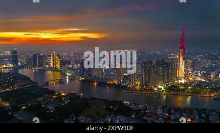 Ein Blick aus der Vogelperspektive auf Ho Chi Minh City bei Sonnenuntergang, lebendiger farbenfroher Himmel, den beleuchteten Wolkenkratzer Landmark 81, den reflektierenden Saigon River in den Lichtern der Stadt Stockfoto