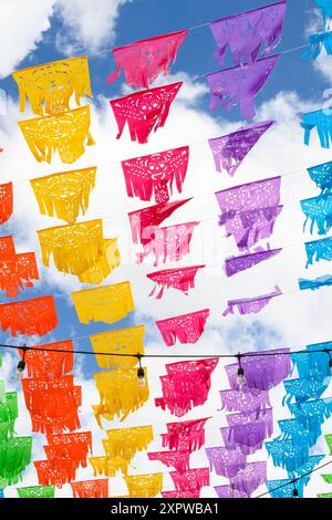 Mexikanische Papel Picado-Dekorationen, die unter einem blauen Wolkenhimmel wehen Stockfoto