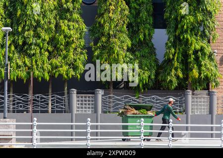 Eine öffentliche Reinigungskraft zieht mit Rädern die Müllrutsche ab, um den gefüllten Müll darin zu entsorgen. Singapur. Stockfoto