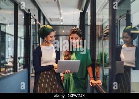 Zwei asiatische Geschäftsfrauen in Freizeitkleidung diskutieren über die Arbeit im Bürokorridor Stockfoto