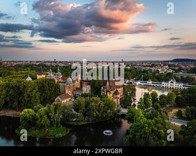 Budapest, Ungarn - aus der Vogelperspektive auf den Stadtpark und den See (Varosligeti to) mit Schloss Vajdahunyad bei Sonnenuntergang. Grünes Laub, dramatischer Sonnenuntergang Himmel und Wolken Stockfoto