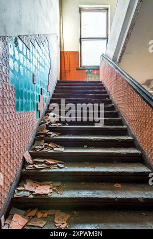 Vorderansicht Des Verlassenen, Kaputten Treppenhauses Mit Zerbröckelnden Roten Tonfliesen In Der Alten Sowjetischen Fabrik Stockfoto