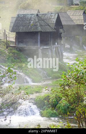 Blick auf traditionelle Wassermühlen, die in der Nähe von Jajce am Pliva-See in Bosnien und Herzegowina gebaut wurden. Wunderschöne Landschaft mit Holzhäusern, Wasser und Nebel Stockfoto