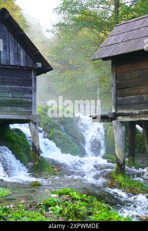 Blick auf das kaskadierende Wasser, Bruchstücke traditioneller Holzmühlen auf Pfählen und Wald im Hintergrund - Umgebung von Jajce (Bosnien und Herzegowina) Stockfoto