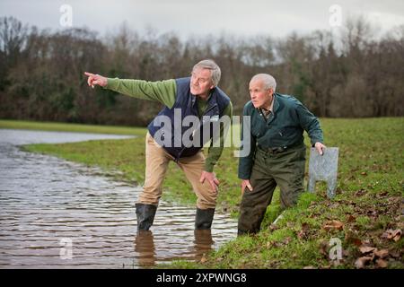 Ein Landwirt und ein Manager des National Trust überprüfen den Entwässerungsauslass an der Hochwasserverteidigung oder der Wasserspeicherbank, die an der aller auf dem Holnicot errichtet wurde Stockfoto