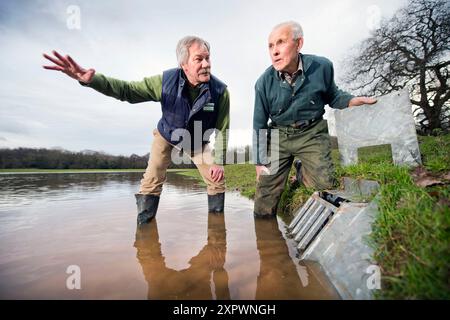 Ein Landwirt und ein Manager des National Trust überprüfen den Entwässerungsauslass an der Hochwasserverteidigung oder der Wasserspeicherbank, die an der aller auf dem Holnicot errichtet wurde Stockfoto