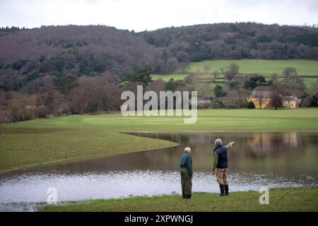 Ein Landwirt und ein Manager des National Trust überprüfen den Entwässerungsauslass an der Hochwasserverteidigung oder der Wasserspeicherbank, die an der aller auf dem Holnicot errichtet wurde Stockfoto