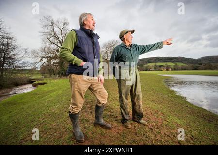 Ein Landwirt und ein Manager des National Trust überprüfen den Entwässerungsauslass an der Hochwasserverteidigung oder der Wasserspeicherbank, die an der aller auf dem Holnicot errichtet wurde Stockfoto