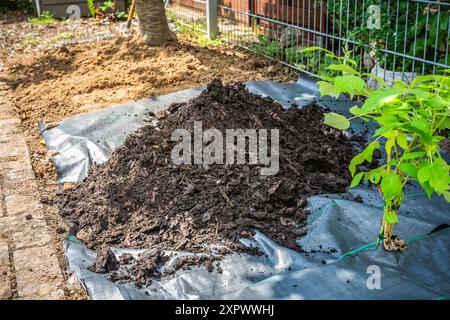 Installation von Unkrautbekämpfungsmaterial und Rindenmulch in einem Wohngarten zur Bekämpfung der Unkrautausbringung Stockfoto