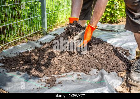 Installation von Unkrautbekämpfungsmaterial und Rindenmulch in einem Wohngarten zur Bekämpfung der Unkrautausbringung Stockfoto