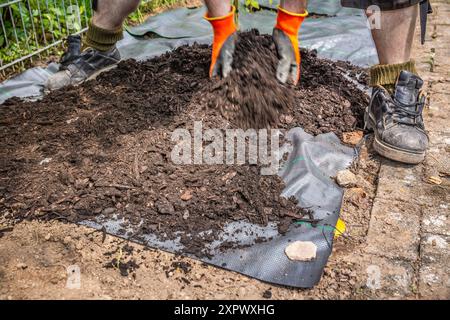 Installation von Unkrautbekämpfungsmaterial und Rindenmulch in einem Wohngarten zur Bekämpfung der Unkrautausbringung Stockfoto