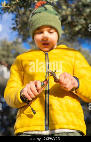 Junge, der einen Stock in der Natur mit einem Rasierer schält an einem Wintertag Stockfoto