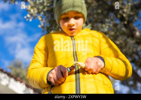 Junge, der einen Stock in der Natur mit einem Rasierer schält, an einem Wintertag mit Kopierraum Stockfoto