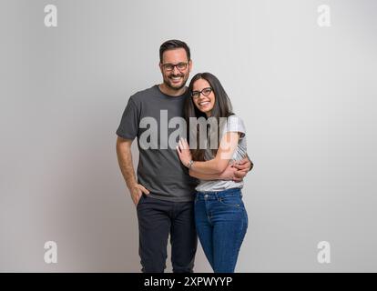 Porträt einer liebevollen jungen Freundin und eines Freundes, der Hände hält und glücklich vor dem Hintergrund steht. Fröhliches Paar mit Brille Embr Stockfoto