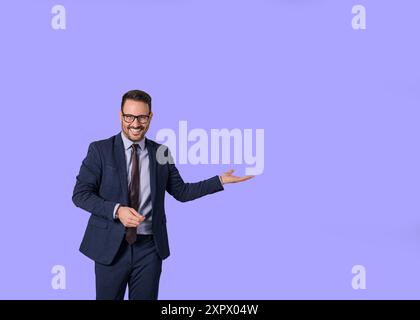Porträt eines lächelnden männlichen professionellen Managers, der Kopierraum für Business-Marketing zeigt. Junger Verkäufer in eleganten Anzügen, der etwas anwarnt Stockfoto