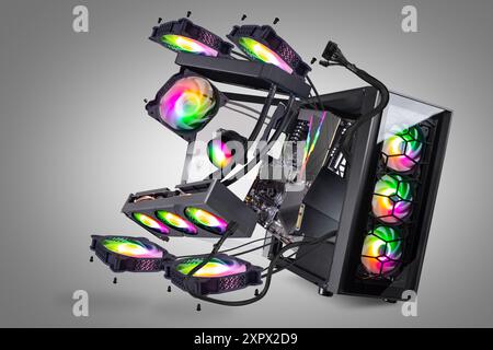 Schwarzer, moderner High-End-Gaming-Computer mit Glasfenstern und bunten Regenbogenleuchten auf grauem Hintergrund. Fliegende Teile und Komponenten pc Stockfoto