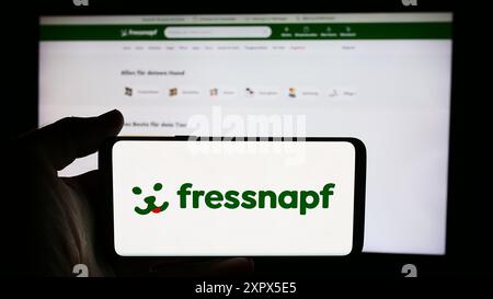 Person mit Mobiltelefon mit Logo der deutschen Einzelhandelsgesellschaft Fressnapf Holding SE vor der Business-Website. Schwerpunkt auf dem Display des Telefons. Stockfoto