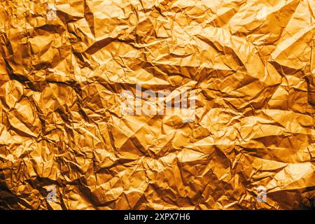 Textur von goldenem Geschenkpapier zerknittert und gefaltet als Designhintergrund, Draufsicht Stockfoto
