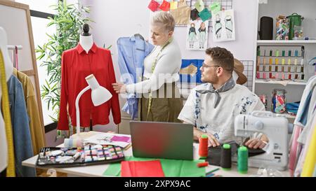 Ein Mann und eine Frau, Designer, arbeiten in einer bunten Schneiderei mit Kleidung und Nähausrüstung. Stockfoto