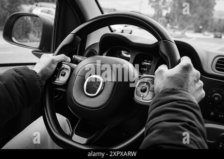 Männer halten das Lenkrad fest, während sie ein Auto auf der Straße fahren. Blick von hinten. Konzept für sicheres Fahren. Die Hände eines Fahrers am Lenkrad von Stockfoto