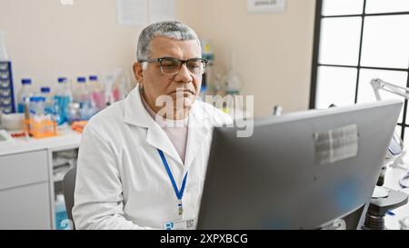 Mann mittleren Alters im Laborkittel arbeitet am Computer im klinischen Labor. Stockfoto